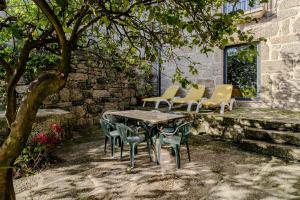 a patio with a table and chairs under a tree at Casa Feixa Gerês in Geres