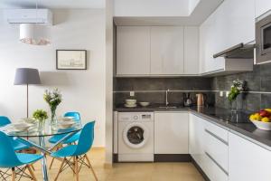 a kitchen with a washing machine and a table with chairs at Apartamento Centro con Parking in Seville +7 photos