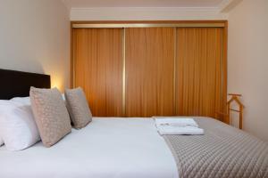 a bedroom with a white bed with a wooden wall at Wander Unwind - Wine Cellars in Vila Nova de Gaia