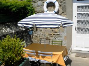 a table and chairs under a striped umbrella at Les Flots Bleus Cancale in Cancale