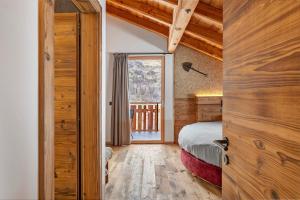 a bedroom with a bed and a large window at Lòni Lodge Vermiglio in Vermiglio