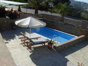 a pool with an umbrella and a chair and a table at Chroma Finikounda 2 in Finikounta +16 photos