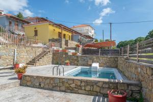 a swimming pool with a stone wall and a house at Chroma Finikounda 2 in Finikounta