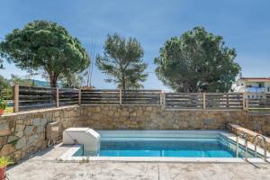 a swimming pool with a stone retaining wall and a fence at Chroma Finikounda 2 in Finikounta
