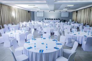 a room filled with white tables and white chairs at Urban Bliss Hotel in Kabwe +60 photos