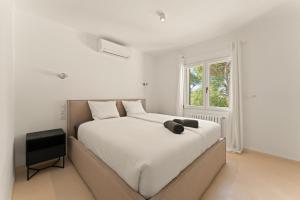 a bedroom with a large bed with white sheets and a window at Casa Baskings in Portopetro +25 photos