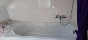 a white bath tub with a shower in a bathroom at Ferienwohnung Am Bahnhof in Hochkirch +6 photos