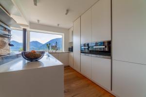 a kitchen with white cabinets and a large window at Levita Living Anima in Tirolo +30 photos