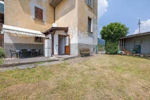 a house with chairs and a table in a yard at Appartamento Ca' Mocc in Porte di Rendena