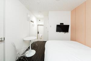 a bedroom with a bed and a desk and a tv at GLOU Akasaka Inn in Tokyo