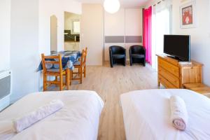 a bedroom with two beds and a tv and a table at Les Mimosas - Appartement 06 in Cazaubon