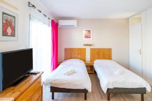 two beds in a room with a flat screen tv at Les Mimosas - Appartement 06 in Cazaubon