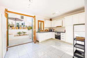 a kitchen with white cabinets and a large glass door at Villa Lucia in Portocolom +16 photos