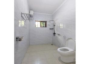 a white bathroom with a toilet and a window at Salpat Camp Lodge in Moshi