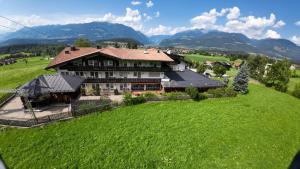 ein großes Haus auf einem Hügel mit einem grünen Feld in der Unterkunft Hotel Heinz in Bruneck