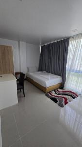 a bedroom with a bed and a window and a chair at joyful theKrisA205 in Ban Lum Fuang