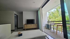 a living room with a tv and a large window at joyful theKrisA205 in Ban Lum Fuang