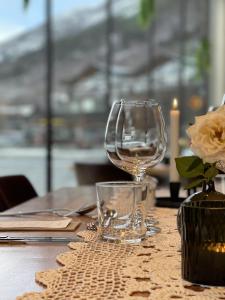 ein Tisch mit zwei Weingläsern und einer Vase mit einer Blume in der Unterkunft BrimiBue Hotel in Lom