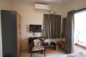 a bedroom with a desk and a chair and a tv at v square inn in Visakhapatnam +20 photos