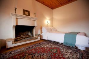 a bedroom with a white bed and a fireplace at Theoni's House in Dhímitra