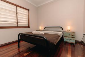 a bedroom with a bed and a dresser and a window at Kimberley Travellers Lodge in Broome