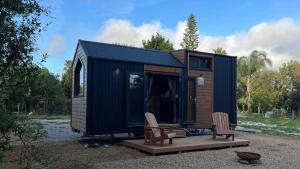 a black tiny house with two chairs and a table at Casa do Cipreste by Tiny Away in São Teotónio