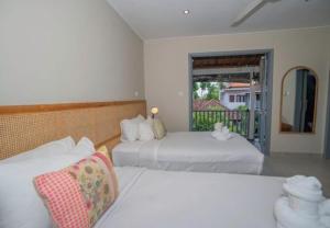 a bedroom with two beds and a balcony at The Peacock Inn in Ubud