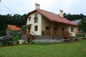 a white house with a red roof in a yard at БУДИНОК сімейних ПРИГОД in Vodniki