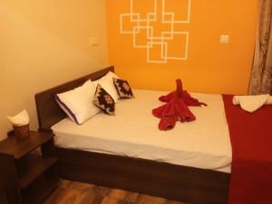 a bedroom with a bed with a red robe on it at Adb's Arangan Kudil Homes in Tiruchirappalli +7 photos