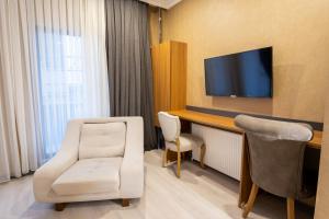 a room with a tv and a white chair and a desk at Orange Hotel & Spa in Şişli