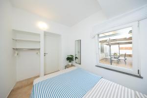 a white bedroom with a bed and a window at Birago22Capri in Capri