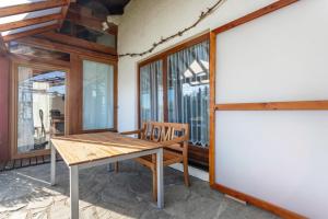 a wooden table and chair in a room with windows at Haus Kali in Teisendorf