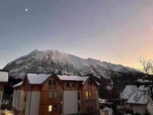 a house with a snow covered mountain in the background at Tauplitzrausch Lodge in Tauplitz