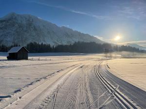 a snow covered field with a barn and a road at Tauplitzrausch Lodge in Tauplitz +3 photos