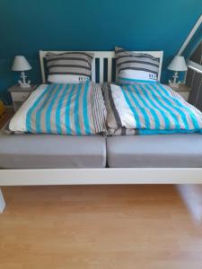 a bed with two pillows and a blue wall at Die Blaue Lagune, Hinter Den Dünen in Prerow