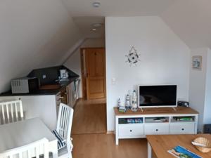 a living room with a table and a television at Die Blaue Lagune, Hinter Den Dünen in Prerow