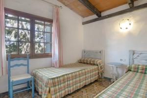 a bedroom with two beds and a chair and a window at Casa Azul - Vejer, El Palmar in Vejer de la Frontera