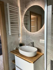 a bathroom with a white sink and a mirror at Czarnowodzianka domki w pierwszej linii brzegowej z widokiem na jezioro in Borsk