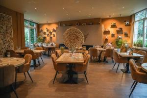 a restaurant with tables and chairs in a room at Hotel Le Charme de la Semois in Alle