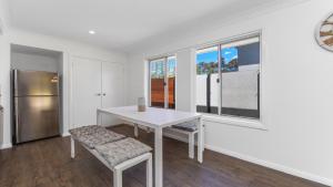 a white dining room with a table and two chairs at 'Coastal Harmony Cottage' by HolidayCo in Hardys Bay