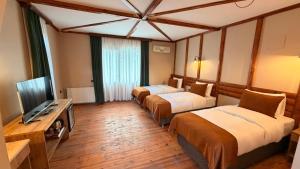 a hotel room with three beds and a flat screen tv at Diamond Koru Hotel in Amasra