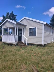 a small house with a porch on a field at Herdman's Rest Farmstay in Lady Grey