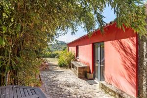 a red building with a bench in front of it at Casa de Andrães Camélias in Marco de Canaveses