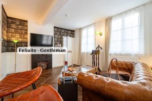 a living room with a leather couch and a television at Boutique Suites anno 1789 by Kamelu in Gengenbach