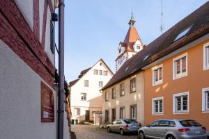 two cars parked in a street with a clock tower at Boutique Suites anno 1789 by Kamelu in Gengenbach