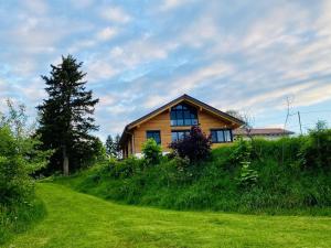 a house on top of a grassy hill at Ferienwohnung Abendsonne in Nagel