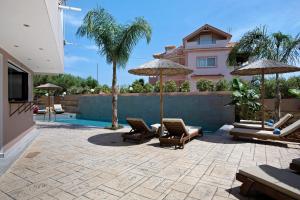 a patio with chairs and umbrellas in front of a house at Villa Dionysia Studio S3 in Alikanas