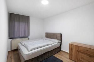 a white bedroom with a bed and a window at Le Quartier Blackforest-Straßburg in Willstätt