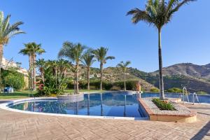 a swimming pool with palm trees in a resort at Casa Palmeras in Almuñécar
