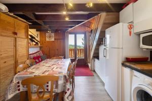 a kitchen with a table with chairs and a refrigerator at Petit chalet mitoyen Pyrénées 2000 in Bolquere Pyrenees 2000